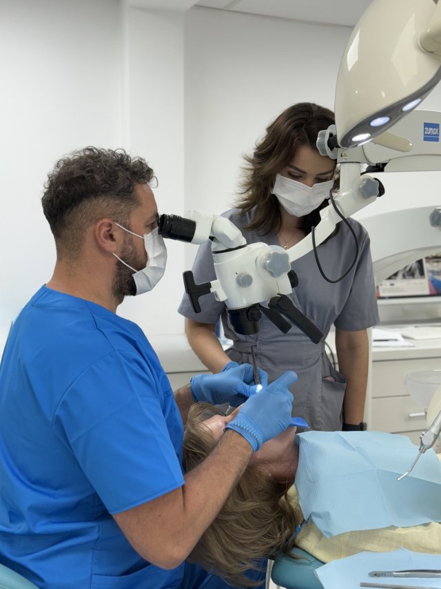 Medic endodont și asistentă Novora în timpul unui tratament de canal la microscop
